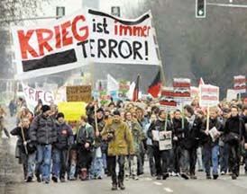 Protest marchers in street with banners saying "Krieg ist immer terror!"
