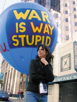 Mary Ann Lyons standing in front of blue balloon "War is way stupid"