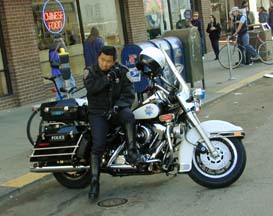 motorcycle policeman looking on, leaning on bike