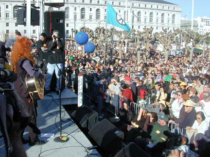 Bonnie Raitt singing with guitar on stage in front of large crowd