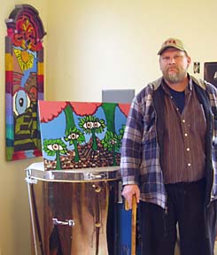 [photo of Dale Howard standing in front of his artwork]