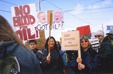 Protesters holding signs reading "No blood for oil!""Got oil?" and "Bad empire, no doughnut"