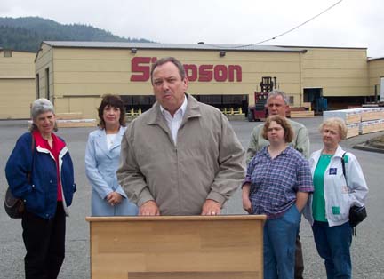 [Bill Jones standing at podium in front of Simpson Timber Co. building,  with five onlookers]
