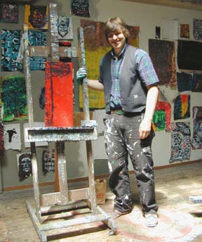 Gus Clark standing next to easel and paintings