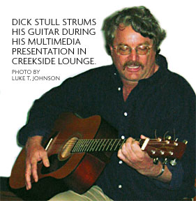 photo of dick Stull, strumming his guitar during ahis multimedia presentation in creekside lounge