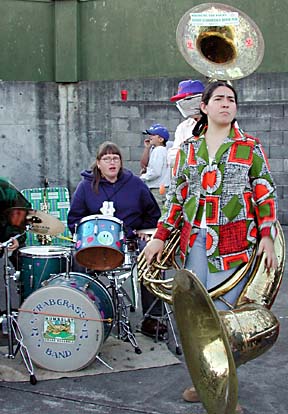Jesica Bishop behind her drumset and Christina Velasquez with sousaphone, watching the game