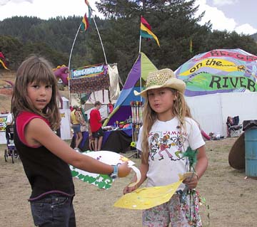 [Ayanna and McKenna with artwork, tents in background]