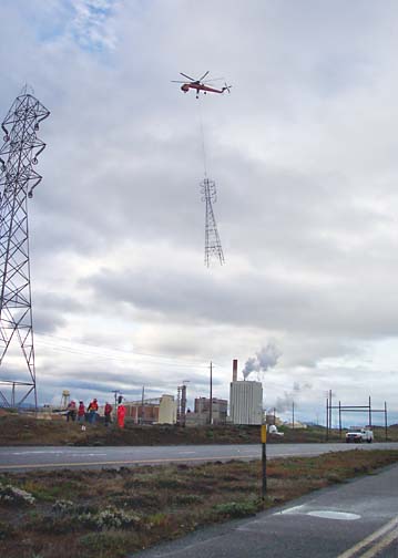Helicopter towing top of electric tower near Samoa mill, workers in foreground