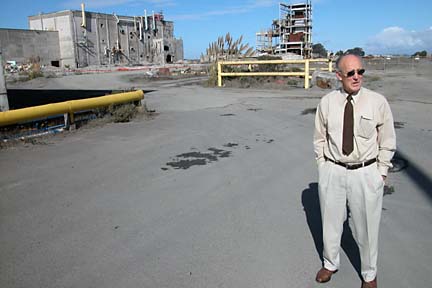 [photo of Dick Lindstrom standing on pavement with old pulp mill in background]
