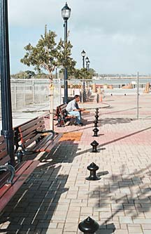 [photo of man sitting on bench on the boardwalk]