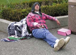 [guy sitting on plaza, hand out]