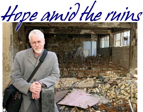 photo of Bruce Cockburn in front of bombed campus theater in Baghdad