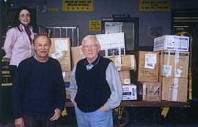 People standing in loading dock of post office, with numerous boxes to be shipped