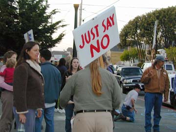[photo of outside protesters, sign reading "just say no"]
