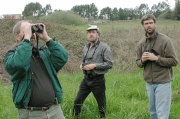 Men with binocolars, standing in marsh area