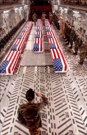 [photo of inside airplane-- flag-draped coffins, military personnel saluting]