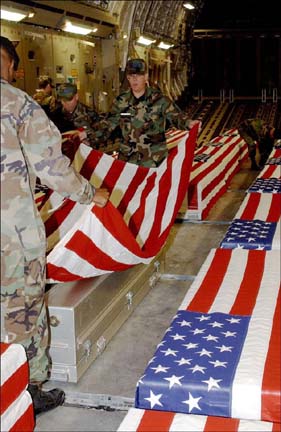 [photo of soldiers covering coffins with American flag]