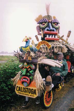 kinetic sculpture with tiki masks, bird, bones, thatch roofing and pilots