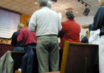 [church attendees standing and singing at a service]