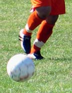 [legs of soccer player with ball]