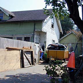house, with full dumpster trailer and hazard cone