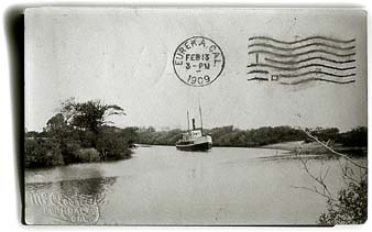 [Photo postcard showing ship on river]