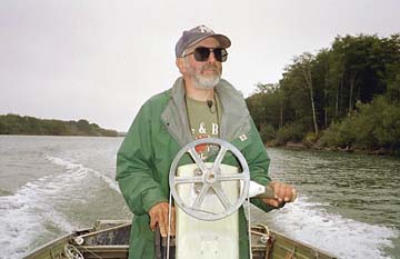 [Slocum piloting boat, river in background]