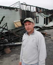 Dave Figueiredo standing in front of burnt-out building