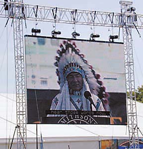 [outdoor video screen with image of W. Richard West speaking]
