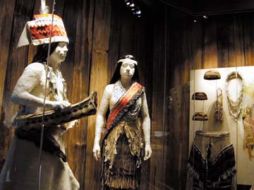 [museum exhibit behind glass of manekins wearing regalia]