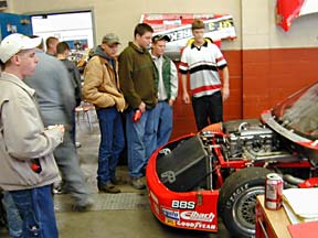 students looking at race car in garage