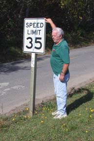 Kallo pointing to top of 35 MPH sign on road