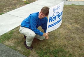 [Chris Kerrigan putting lawn sign in yard]