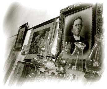 Old framed photos hanging on a wall and glass lanterns on display in museum